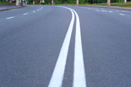 The asphalted road with two continuous white strips. The highway with a white marking. Turn on the road. Concept long way, beginning somethingの写真素材
