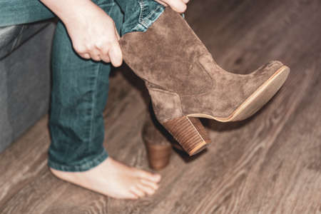 close-up. Shoe fitting. Female hands put on a boot on a leg. The girl puts on footwear. Concept of buying, trying on shoes and boots.の写真素材