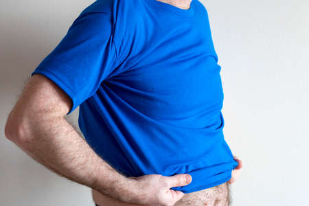Man dresses, tries on a T-shirt. man wearing t-shirt and jeans, standing. Concept fitting trying on...