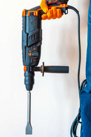 workman with a rotary hammer. worker, professional with hammer drill perforator.