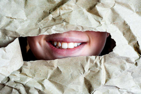 Smile with teeth in holes. mouth in hole in a crumpled paper background.の写真素材