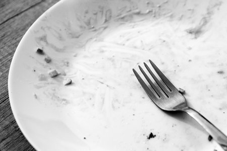 DIRTY PLATE AND TABLEWARE AFTER a MEAL. Top view of empty plate, dirty after the meal is finished. black and white photoの写真素材
