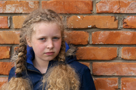 unhappy teenager. Portrait of a teenager against a wall. Depressed girl. Gloomy child on brick...