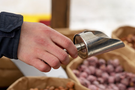 A hand with a scoop and a hand take nuts. mixed nuts hazelnuts, walnuts, cashews, pine nuts on...