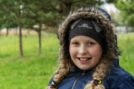 A teenager in a warm jacket. warmly dressed girl in a hat and with pigtails. Portrait of a beautiful...