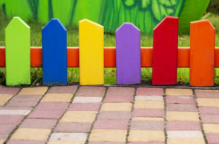 colored small fence. close-up colored decorative wooden palisade, paling. paving stone against the background of a color hedge, railing. Copyspaceの写真素材