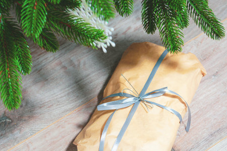 A roll of paper tied with a ribbon under a fir tree. Present. Christmas gifts conceptの写真素材