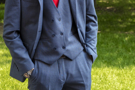 Man in a suit. Gray three-piece costume. Hands in trouser pockets. Business suit