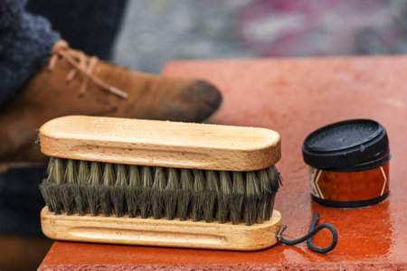 Shoe cream, brush close-up. Cleaning of boots on the street. Concept wrong care of footwear. Man's...