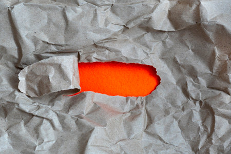 hole in paper with color paper background inside. Good paper texture.torn hole in paper.paper ripped to create a holeの写真素材