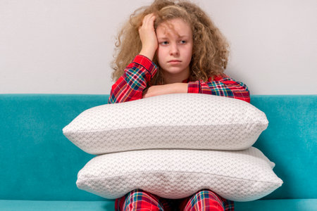 girl sitting with pillows on bed. Pillows on the girl's lap. Concept of a good, sound sleep. young...