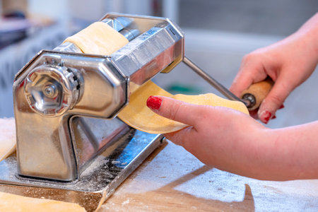 Pasta maker. dough Woman's hand. The concept of making dough and pasta at home. Preparing fresh...