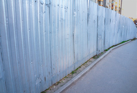 A metal fence along the sidewalk. Fences of the construction site. enclosure, fencing, guardの写真素材