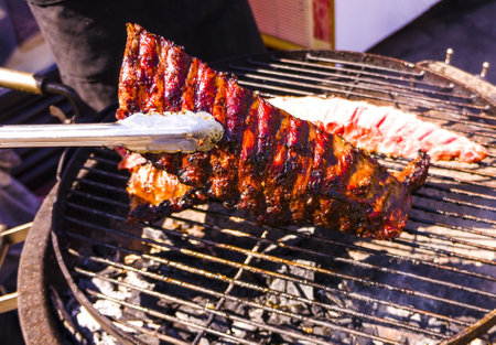 The cook holds edge nippers on a grill. Preparation of meat on a grill. Edges with meat fried on a grillの写真素材