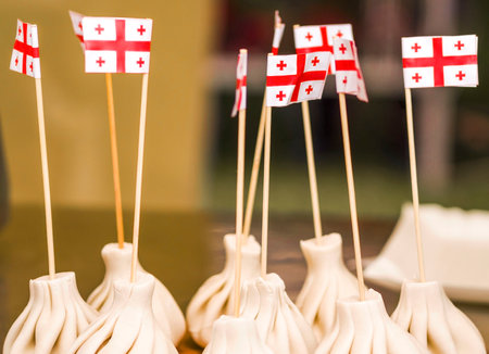 Khinkali (pelmeni) national dish of Georgia. Flags of Georgia over traditional food. Concept Hospitable country of Georgiaの写真素材