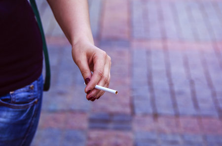 The woman holds a cigarette in hand. Smoking concept, smoker. close-up. Threat of life of women. Addiction. Quitting smoking concept. The social problem.の写真素材
