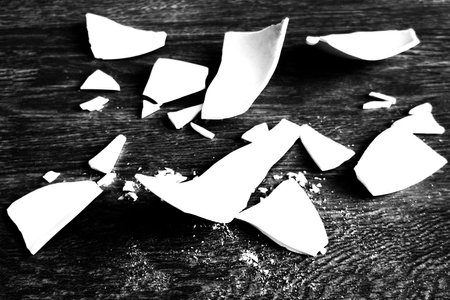 Splinters and Fragments of the broken white ware. Broken Plate, glass. Pieces of shattered dishes. close-up, side view. Black and white photoの写真素材