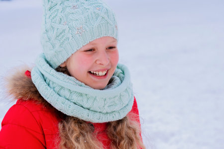 Portrait of the happy child in the winter.The girl against the background of snow.The cheerful child in warm clothes in the winter. Winter scene. Time of winter vacation.の写真素材