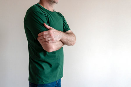 Man dresses, tries on a T-shirt. man wearing t-shirt and jeans, standing. Concept fitting trying on clothes. Copy spaceの写真素材