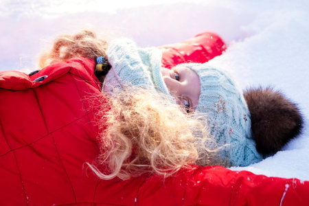 The girl against the background of snow. The cheerful child in warm clothes.Winter scene. Time of winter vacation.の写真素材