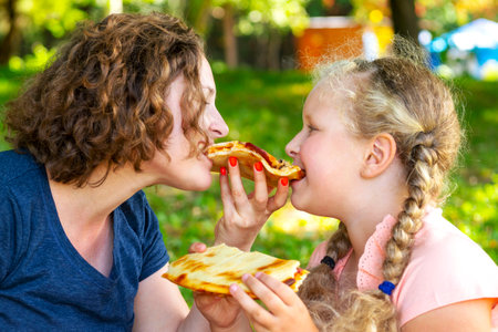 Mother and the daughter eat pie. family picnic. The woman and the girl eat pie together. Concept of leisure of family, outdoors, picnicの写真素材