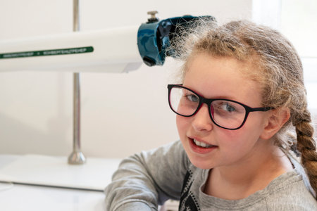 A girl is sitting in front of a device for stimulating vision.Ophthalmic equipment.The concept of...