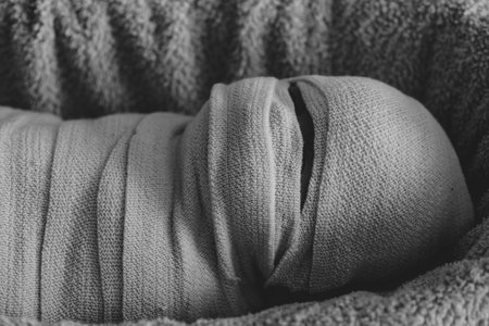 The man is wrapped in a cloth. The body is shrouded in a veil. The concept of a Muslim deceased. Mummy in the background.Funeral concept, before burial. Black and white photoの写真素材