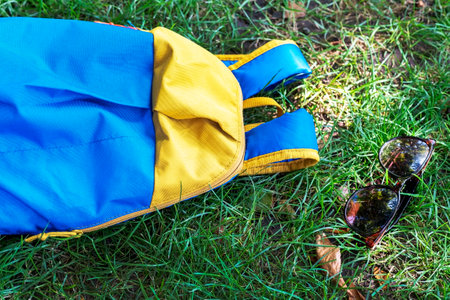 Backpack and sunglasses on a lawn. Concept outdoor recreation. Picnic