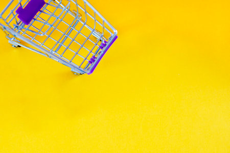 cart, hand-cart, shopping cart, trolley on a yellow background. concept buyer, shopper. purchasing power, demand, shopping concept. copy spaceの写真素材