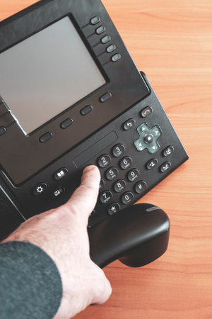 The hand holds a phone tube. Close-up. Dialing a number with your hand. The man's hand presses the...