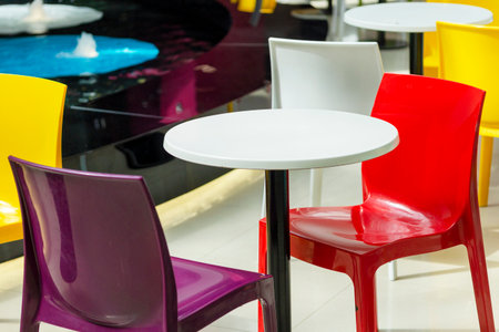 Color stools to premises of shopping center. Chairs of different color near a table with a whiteの写真素材