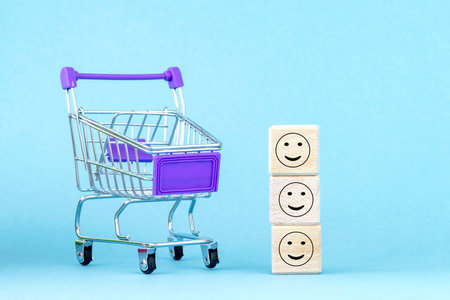 Wooden cubes with smiling faces. basket, cart. purchase, buy concept. buying or selling goods or servicesの写真素材