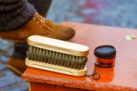 Shoe cream, brush close-up. Cleaning of boots on the street. Concept wrong care of footwear. Man's...