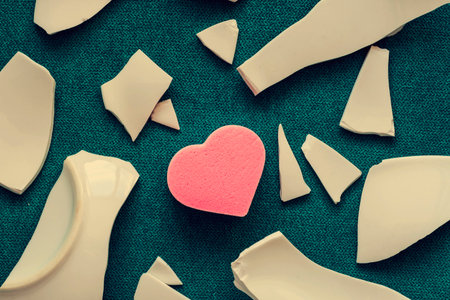 Heart among the fragments. Symbol of unhappy love. Bad health concept. White shards and heart. top viewの写真素材