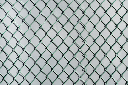 A full-frame background of an iron wire grid on a wall featuring various metallic tints and shadows.
