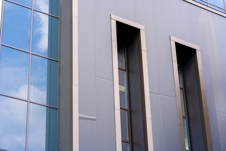 A sharp, detailed shot of a modern architectural facade made of glass and metal panels in an urban...