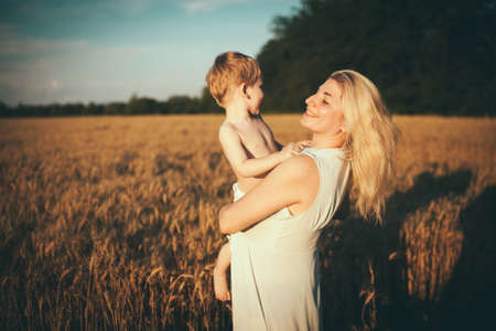 Mom and son having fun by the lake, field outdoors enjoying nature. Silhouettes on sunny sky. Warm...