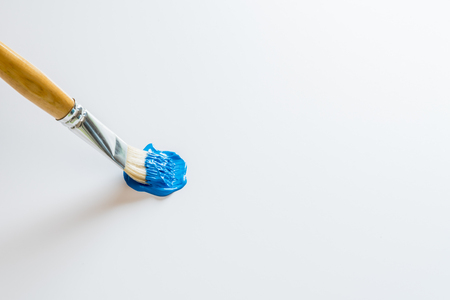 Hobby artist painting with blue acrylic paint on white foam boardの写真素材