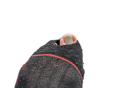 A close up of smily painted toe nail lurking out of a torned sock.の写真素材