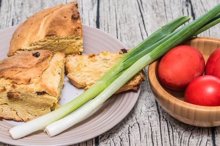 Red Easter eggs in a bamboo bowl with spring onion and sweet easter bread. Istrian Pinca bread. Red eggs are traditionally important during the observation of Orthodox Easter. Served on a table with wooden pattern as a background.の写真素材