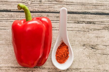 Red pepper and paprika spice in small spoon on a wooden backgroundの写真素材