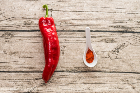 Red pepper and paprika spice in small spoon on a wooden backgroundの写真素材
