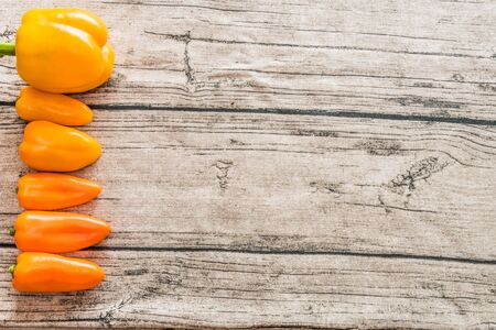 A mix of various sized peppers on a wooden background.の写真素材