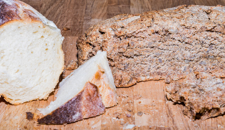 Delicios home made rye bread and regular white bread on a wooden board.の写真素材