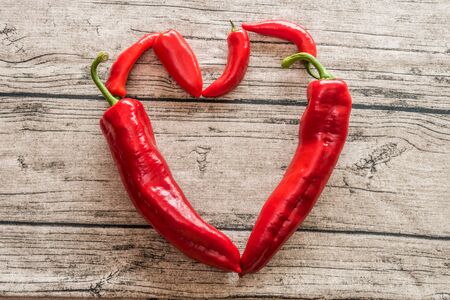 A mix of various sized peppers on a wooden background.の写真素材