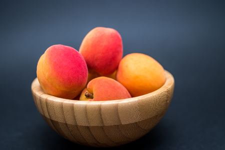 A heap of fresh apricots in a bamboo bowl on a dark backgroundの写真素材