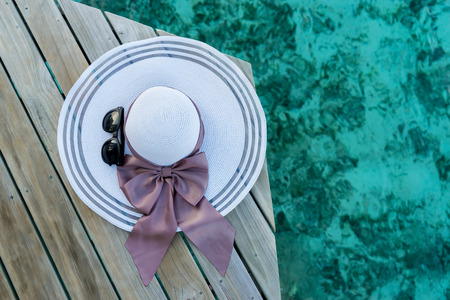 hat and sunglasses on wood terrace,sea background.の写真素材
