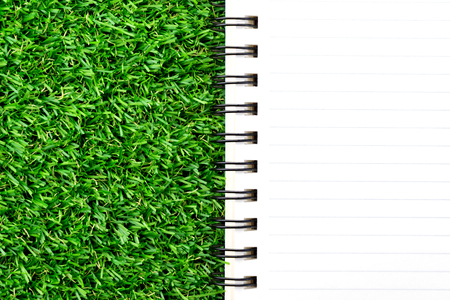 Orange notebook on green grass.の写真素材