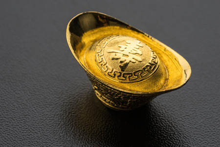 Closeup of big gold on black background. Chinese word mean wealthyの写真素材
