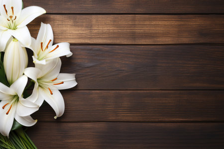 Beautiful lily flowers on brown wooden table, flat lay. Space for textの素材